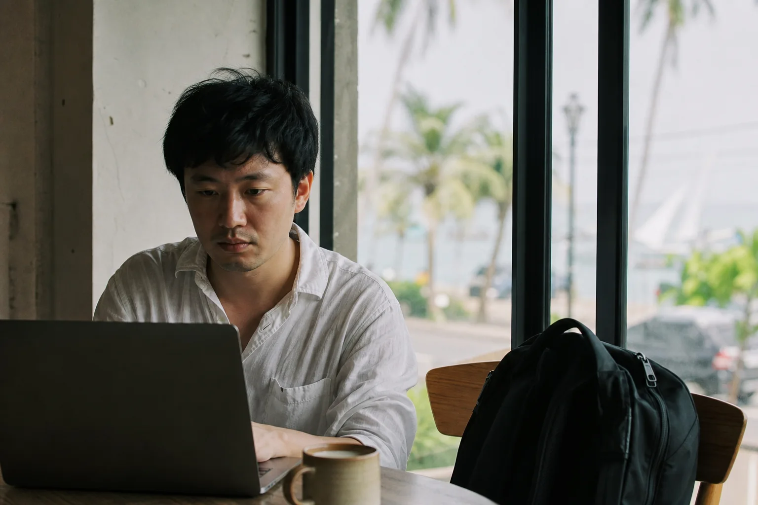 海外の窓辺でノートパソコンに向かう講師